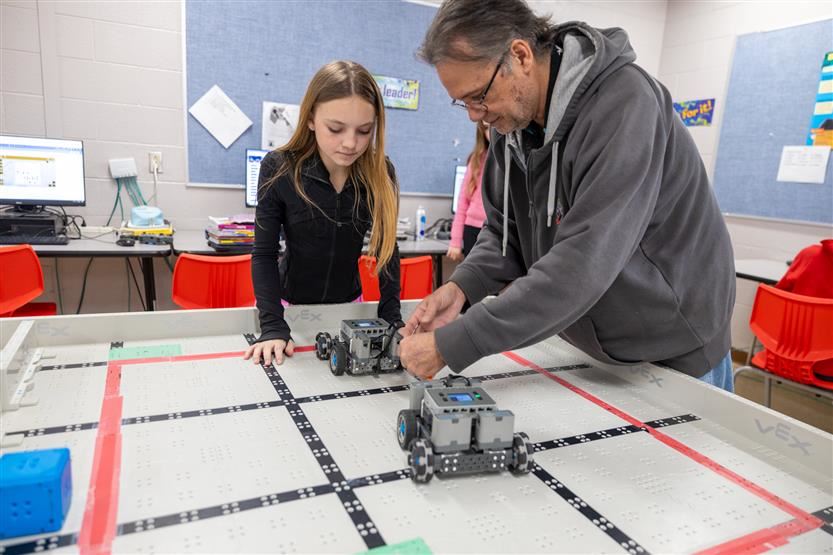  Student and Teacher working with robots.